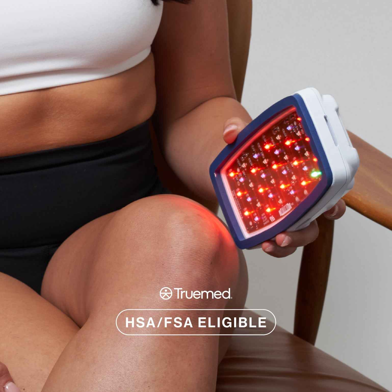 Woman applying Celluma POD II LED red light therapy to thighs for targeted body contouring.