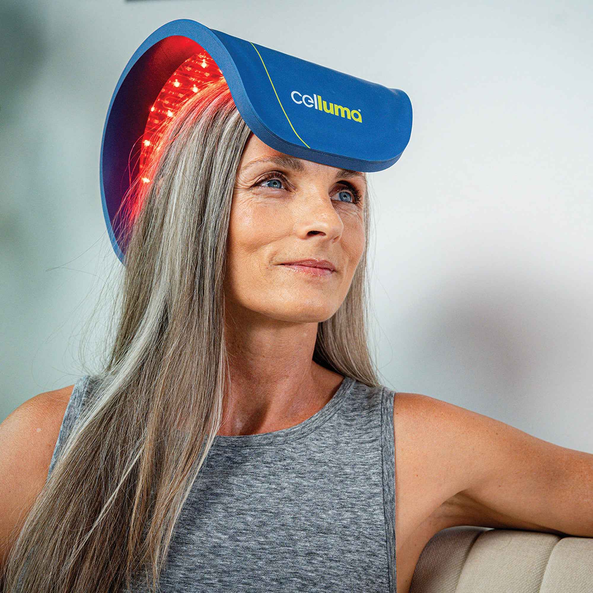 Woman using Celluma RESTORE II LED panel with hair serum for targeted hair regrowth and scalp care.