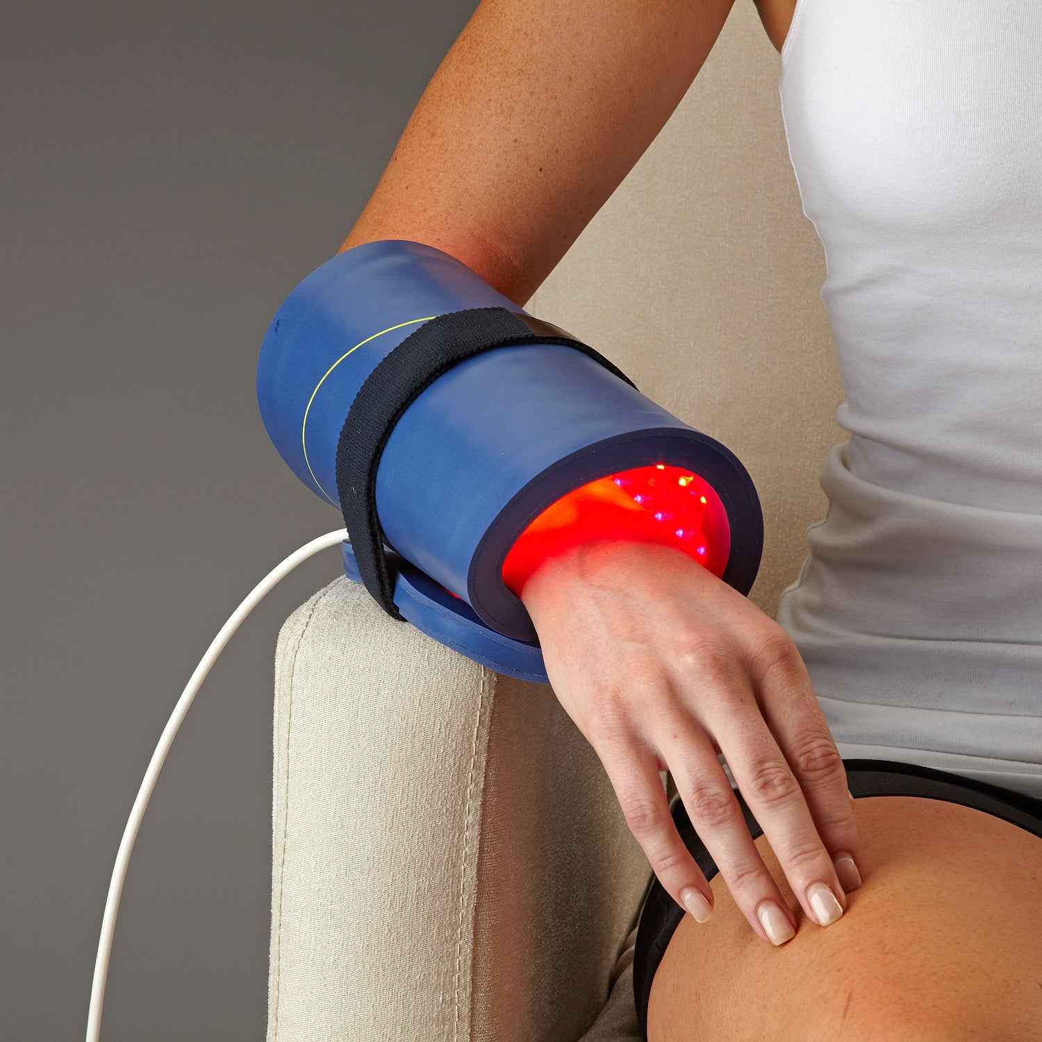 Woman using Celluma RESTORE LED Red Light Therapy to treat hand pain. 