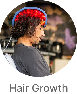Person wearing a red light hair growth device in a blurred indoor setting